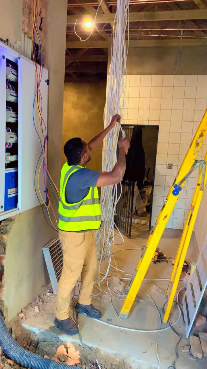 Electrician pulling cables through the ceiling from a ladder